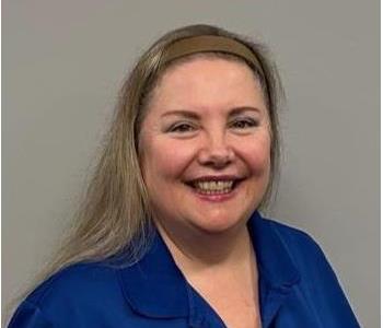 Woman with blonde hair and a blue shirt with a servpro logo on it