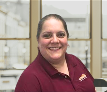 smiling woman with hoop earrings and a maroon Servpro shirt on