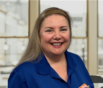 Woman with blonde hair and a blue shirt with a servpro logo on it