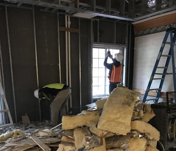 Servpro employee pulling down insulation from the ceiling