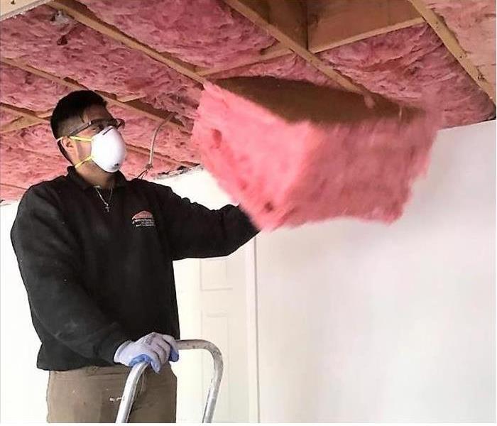 Man removing insulation from a ceiling