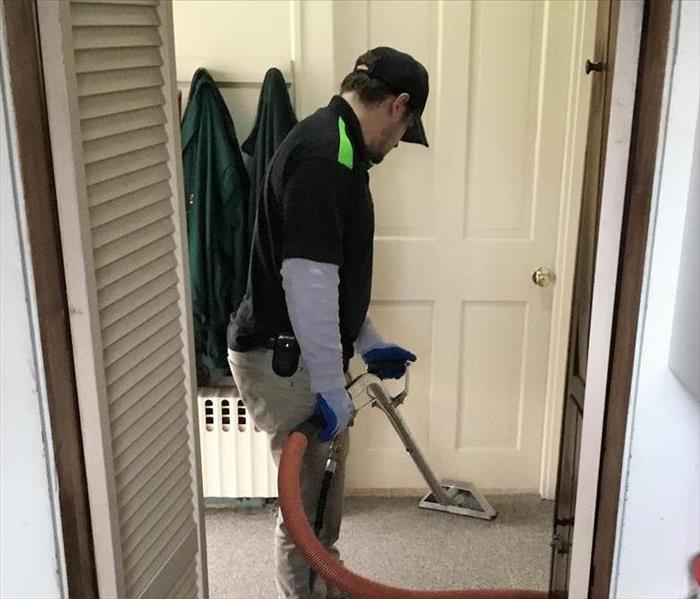 man in servpro uniform vacuuming floor