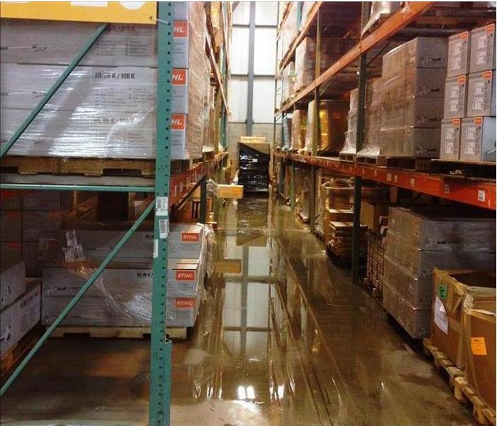 warehouse with shelving that has several inches of water on the floor