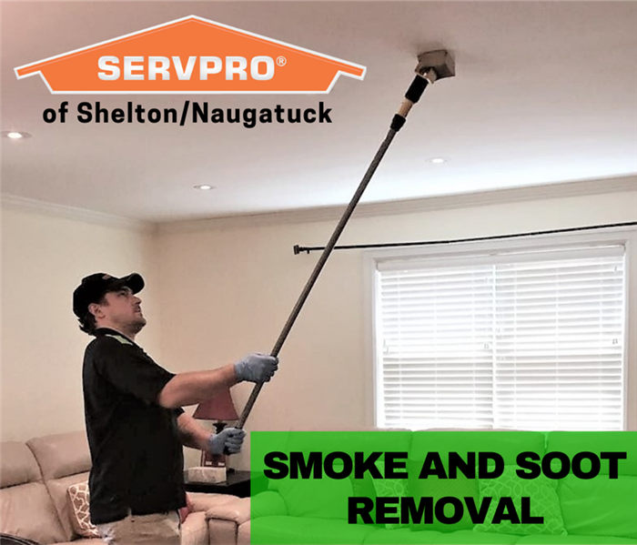 man in servpro shirt and hat cleaning a ceiling